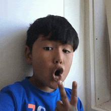 a young boy wearing a blue shirt with the number 7 on it is making a funny face