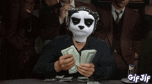 a man wearing a panda mask is counting money at a table