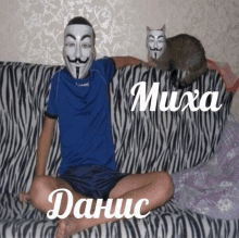 a man wearing a anonymous mask sits on a zebra print couch with a cat