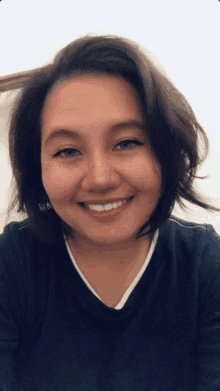 a woman with freckles on her face is smiling and wearing a blue shirt