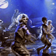 a group of people are dancing on a stage in front of a blue background .