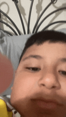 a young boy is laying on a bed and making a face