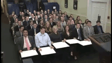 a large group of people are posing for a photo in a room