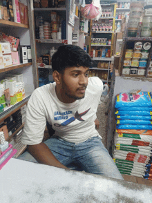 a man wearing a white shirt that says hankaza mikato sits in a store