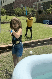 a boy and a girl are playing with water balloons in a pool