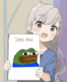 a girl is holding a piece of paper with a picture of a frog on it .