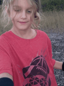 a girl wearing a red t-shirt with a football on it