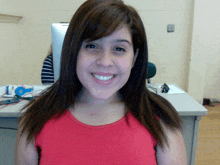 a woman in a red shirt is smiling in front of a computer