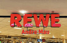 a sign that says rewe andre mau in red letters