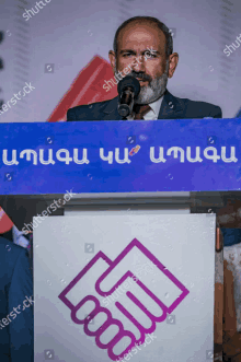 a man stands at a podium with a sign that says shutterstock on it