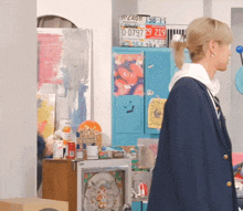 a woman in a blue jacket stands in front of a locker with a license plate that says 10 07979 219