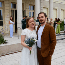 a bride and groom pose for a picture in front of a crowd of people