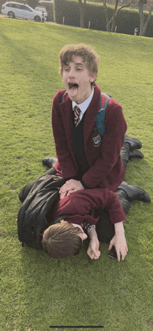 a boy in a school uniform is laying on another boy 's lap