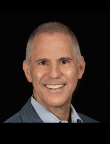 a man with gray hair and a blue shirt is smiling