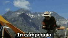 a man in a straw hat is sitting in front of a mountain with the words in campeggio written above him