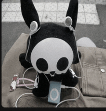 a stuffed animal with a skull on its head is listening to music on an ipod