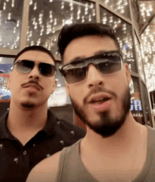 two men wearing sunglasses are standing next to each other in front of a sign that says ga