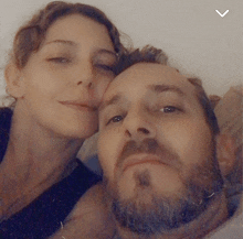 a man with a beard and a woman with curly hair are posing for a picture together