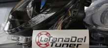 a sign that says latanadel tuner sits next to a pair of headlights