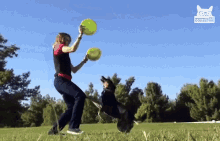 a woman playing frisbee with a dog in a field with a cat in the background that says " college "