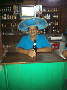 a man wearing a sombrero sits at a bar holding a beer