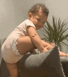 a baby in a diaper is sitting on a couch and smiling