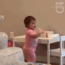 a little girl in a pink shirt is standing in front of a table with the word hop pilu on the wall behind her