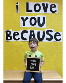 a boy is holding a sign that says you love me