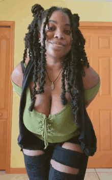 a woman with dreadlocks wearing a green top and black shorts