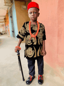 a little boy wearing a red hat and a cane