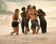 a group of people are standing on a beach hugging each other