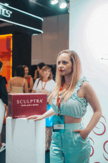 a woman stands in front of a box that says sculptra on it