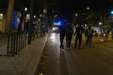 a group of people walking down a street at night with an arrow pointing to the right