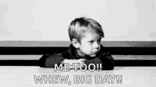 a black and white photo of a little boy sitting at a table with his hand on his face .