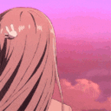 a close up of a girl 's hair with a pink sky in the background .