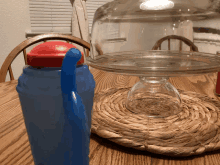 a blue water bottle sits on a table next to a glass dome