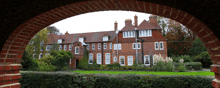 a large brick building with a lot of windows is behind a brick archway