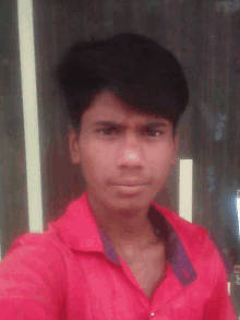 a young man wearing a red shirt takes a selfie