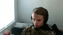 a young man wearing a camo jacket and headphones with the word crux on the back