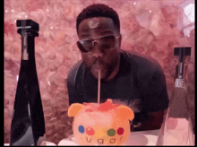 a man wearing sunglasses is blowing out a candle in a piggy bank that says ugo