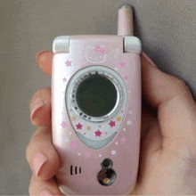 a person is holding a pink flip phone with a hello kitty design on it .