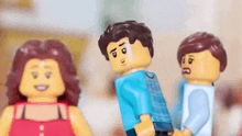 a group of lego figures are standing next to each other holding hands .