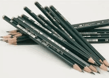 a bunch of black pencils stacked on top of each other on a white surface .