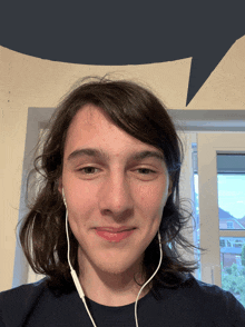 a young man wearing earbuds looks at the camera with a speech bubble in the background