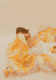 a woman in a yellow and white dress lays on the floor