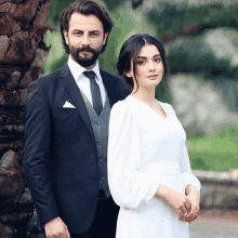 a man in a suit and tie and a woman in a white dress pose for a photo