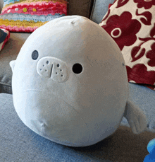 a stuffed seal is sitting on a couch in front of a crocheted blanket