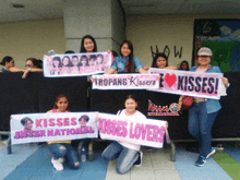 a group of women holding up signs that say kisses