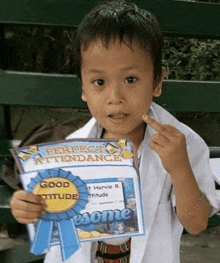 a young boy is holding up a certificate that says perfect attendance