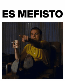 a man sitting in a chair with a cup in his hand and the words es mefisto above him